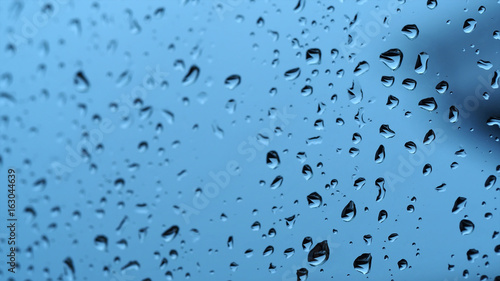 Rain drops on window with blue color background