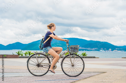 carefree woman with bicycle riding by the sea having fun and smiling