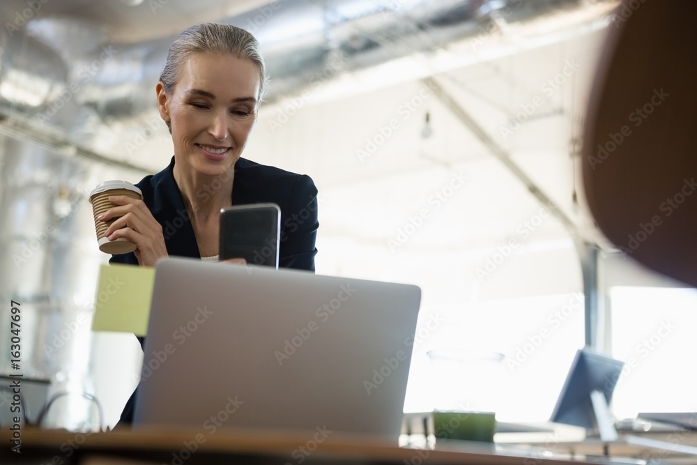 Businesswoman using smart phone while sitting at table