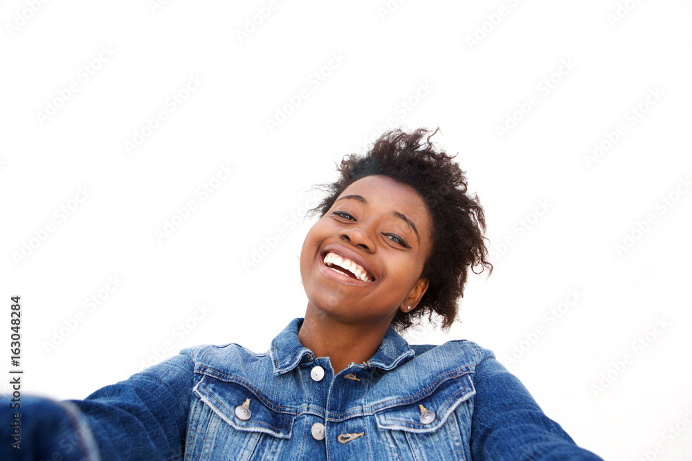 Close up smiling young afro american girl taking selfie against white background Close up smiling young afro american girl taking selfie against white background