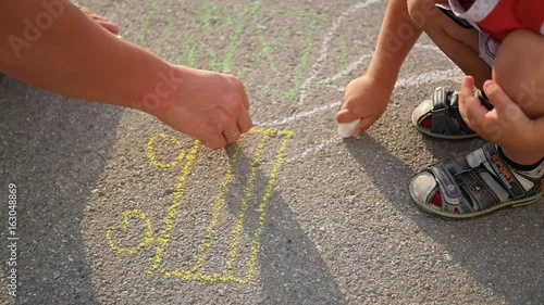 family with child draws with chalk on the asphalt. games outdoors