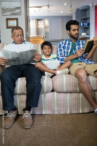Boy with father and grandfather sitting on sofa