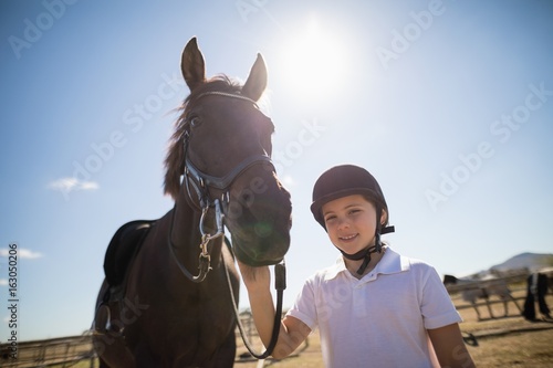 Rider girl standing with a horse in the ranch