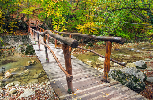 Wooden bridge in the autumn forest. Crossing the small river into The Grand Canyon of the Crimea