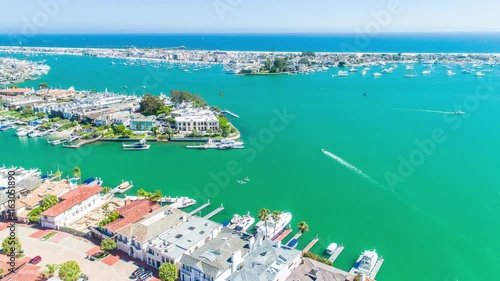 Aerial footage from the drone over Newport Beach harbor and Linda Isle with boats, yachts, blue skies, beach homes and the Pacific Ocean in the back.