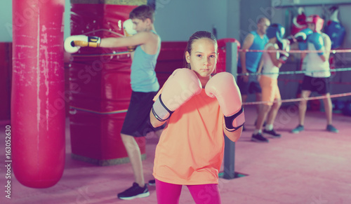 Girl in gloves posing during boxing training at gym