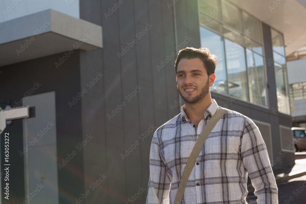 Smiling man looking away while standing by building Smiling man looking away while standing by building