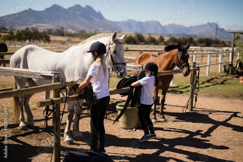 Two girls keeping saddle on fence © wavebreak3