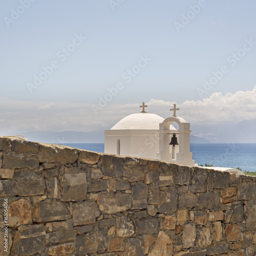 Greek orthodox church behind the stone wall near the beach