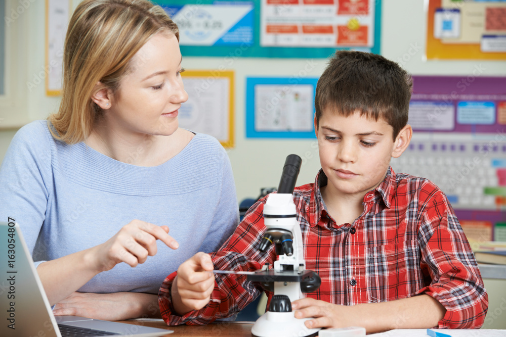 Teacher With Male Student Using Microscope In Science Class Teacher With Male Student Using Microscope In Science Class