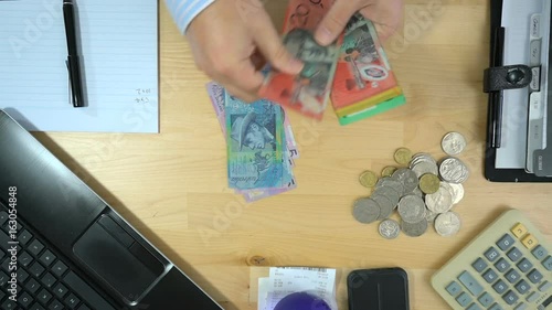 Business man counting cash at desk overhead, counting notes, real time.