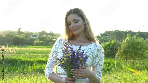 Beautiful woman in white dress with flowers on the meadow slow motion