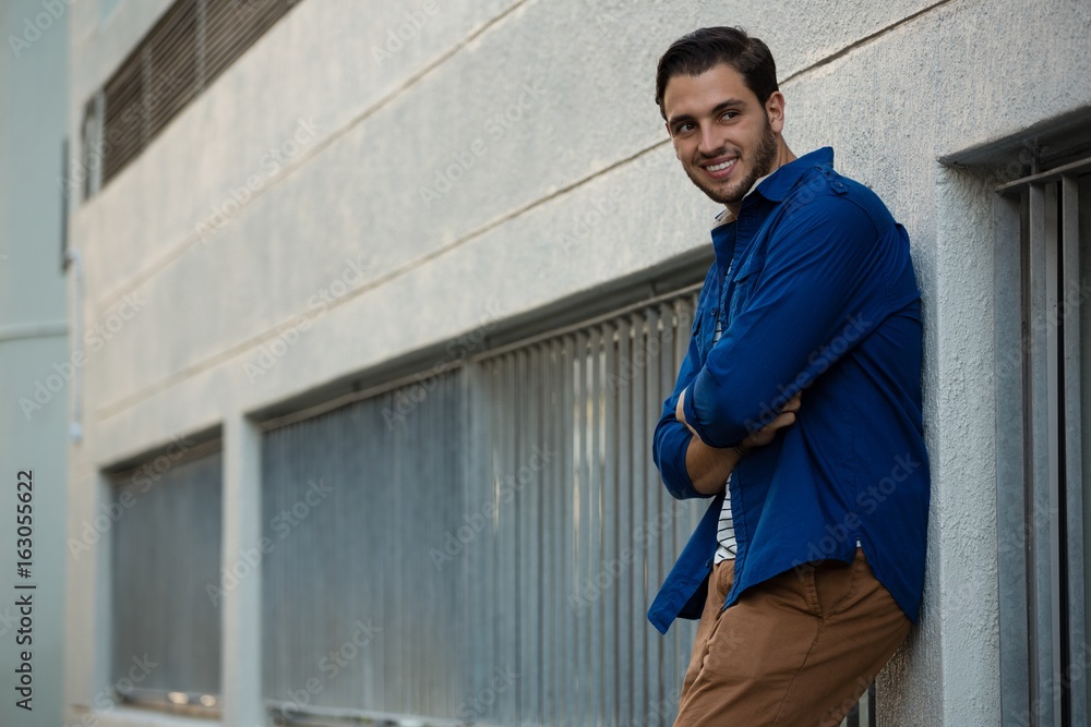 Smiling young man with arms crossed leaning on wall Smiling young man with arms crossed leaning on wall