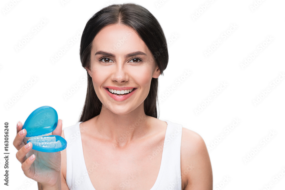 Happy girl holding transparent plastic teeth for orthodontic correction Happy girl holding transparent plastic teeth for orthodontic correction
