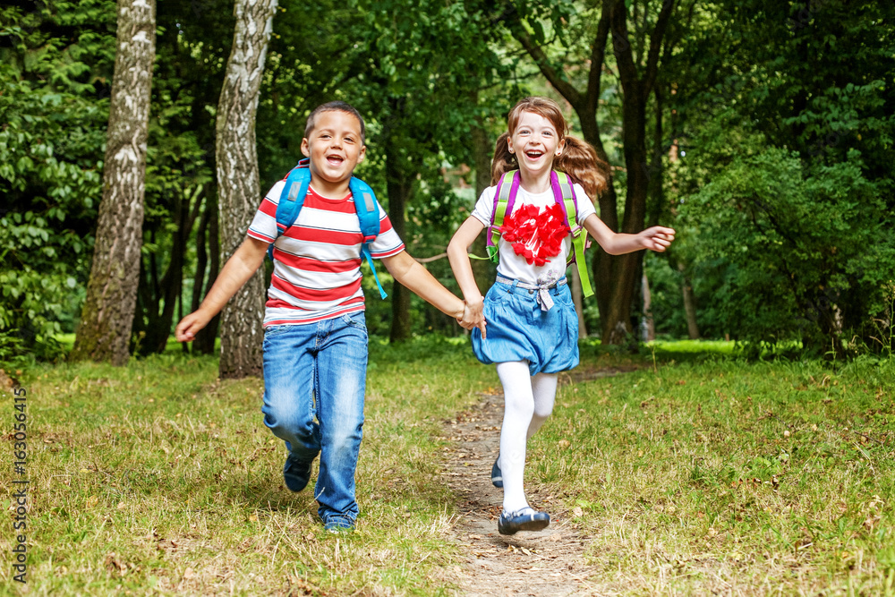 Children hold hands. Students running in the park. The concept is back to school.