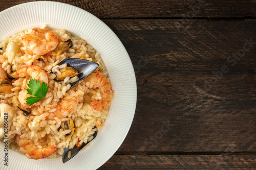 Seafood risotto on dark rustic background with copyspace