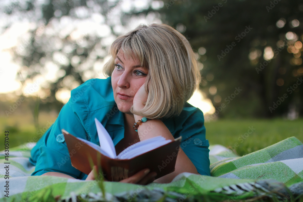woman in park with book on the grass woman in park with book on the grass