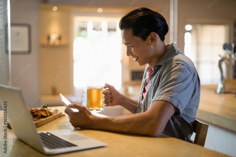 Man using digital tablet while having beer in restaurant Man using digital tablet while having beer in restaurant