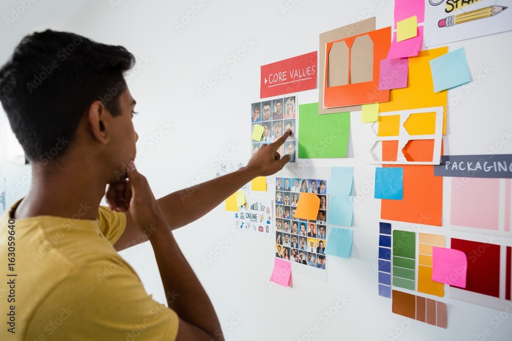 Man pointing at sticky notes in office Man pointing at sticky notes in office