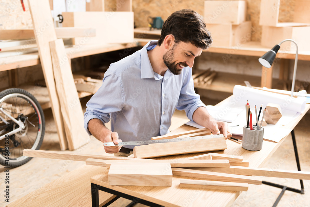 Happy bearded wood master working with timber strips in workshop Happy bearded wood master working with timber strips in workshop