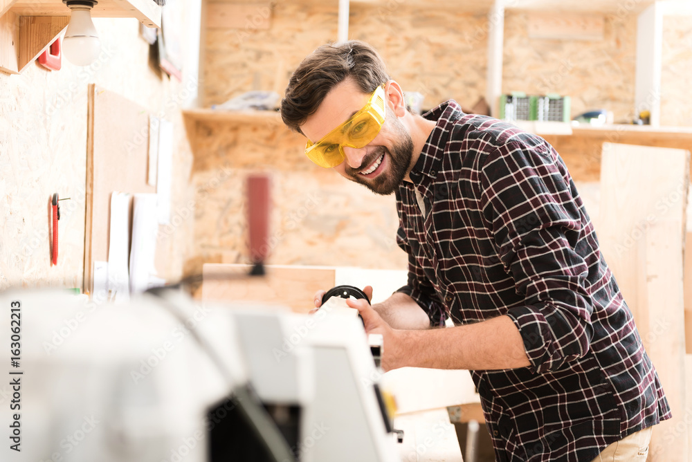 Joyful young woodworker is enjoying his work