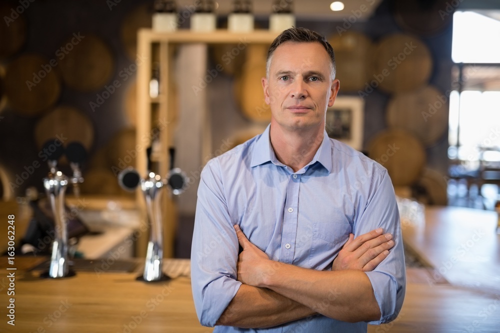 Obraz premium Man standing with arms crossed near bar counter
