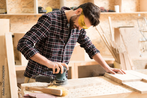Attractive energetic carpenter is standing at his job