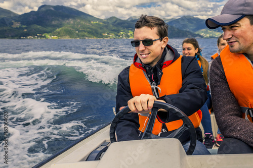 Portrait of young and cheerful man close up driving the motorboat, Norway. He is enjoying the moment.