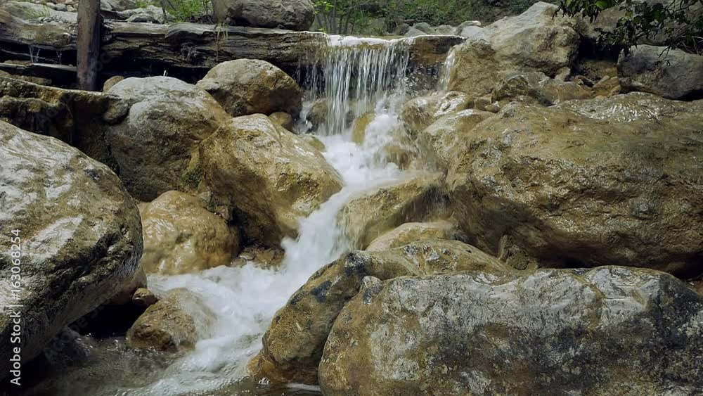 Clean mountain water in the rocks small waterfall slow motion Clean mountain water in the rocks small waterfall slow motion