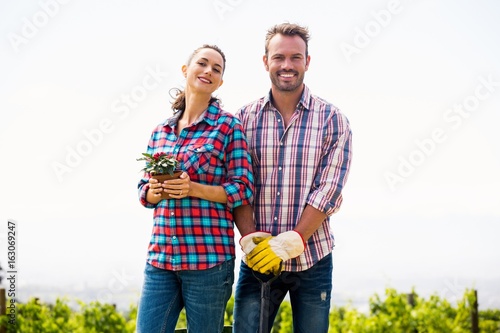 Portrait of smiling woman with man holding potted plant
