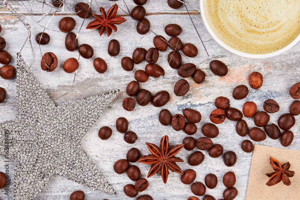 Coffee decorations on wooden background. Silver star and coffee beans. Coffe and festive mood.