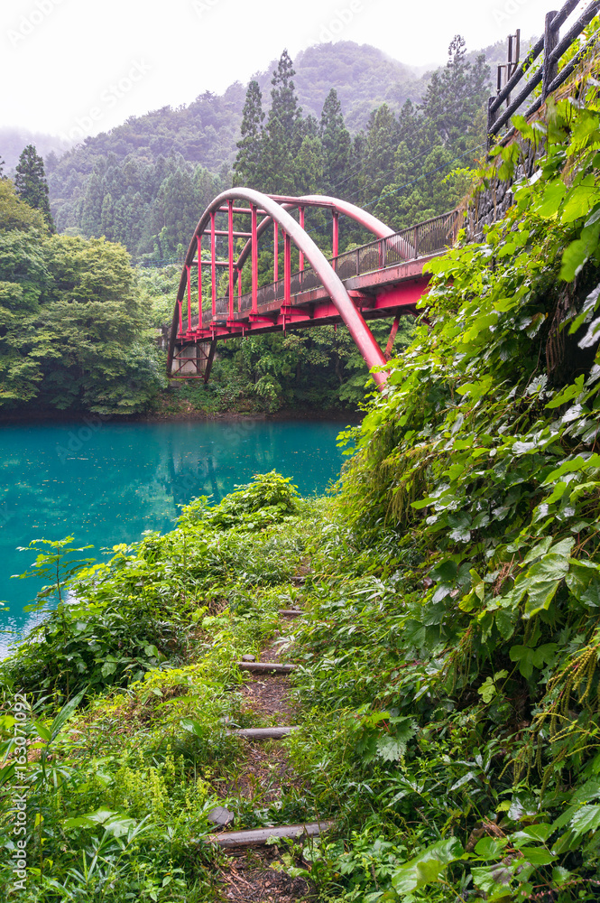 Landscape with view of red arch bridge and vivd blue lake in the forest Landscape with view of red arch bridge and vivd blue lake in the forest