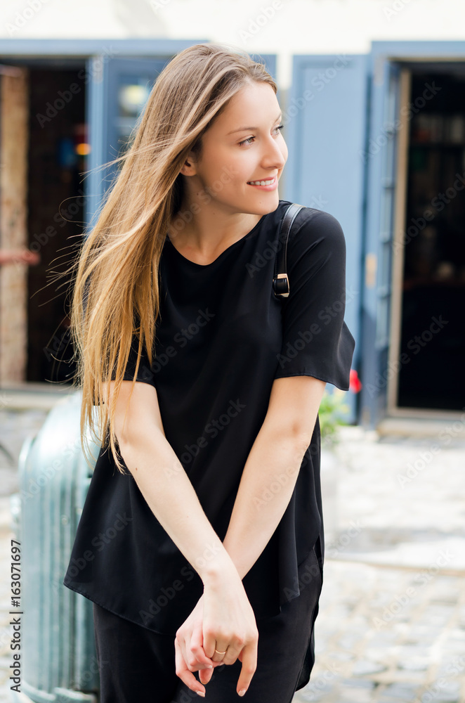 Outdoor portrait of young attractive woman with long blonde hair walking in the city