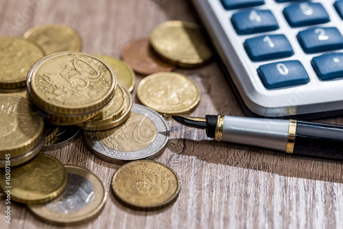 euro coina with pen and calculator on desk photo