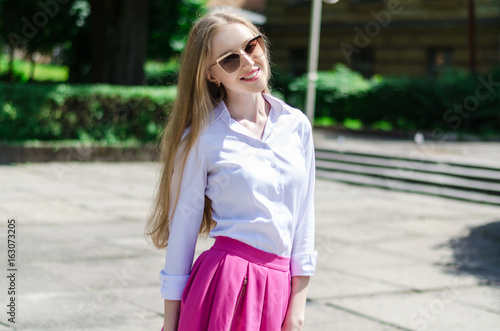 Outdoor summer portrait of a young attractive lady walking in the park