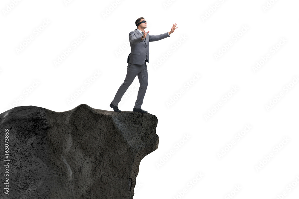 Blindfold businessman standing on tip of cliff Blindfold businessman standing on tip of cliff
