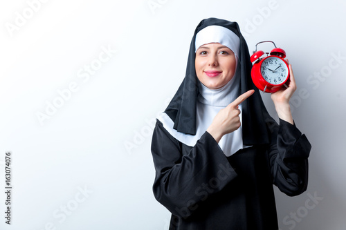 Young smiling nun with red alarm clock © Masson