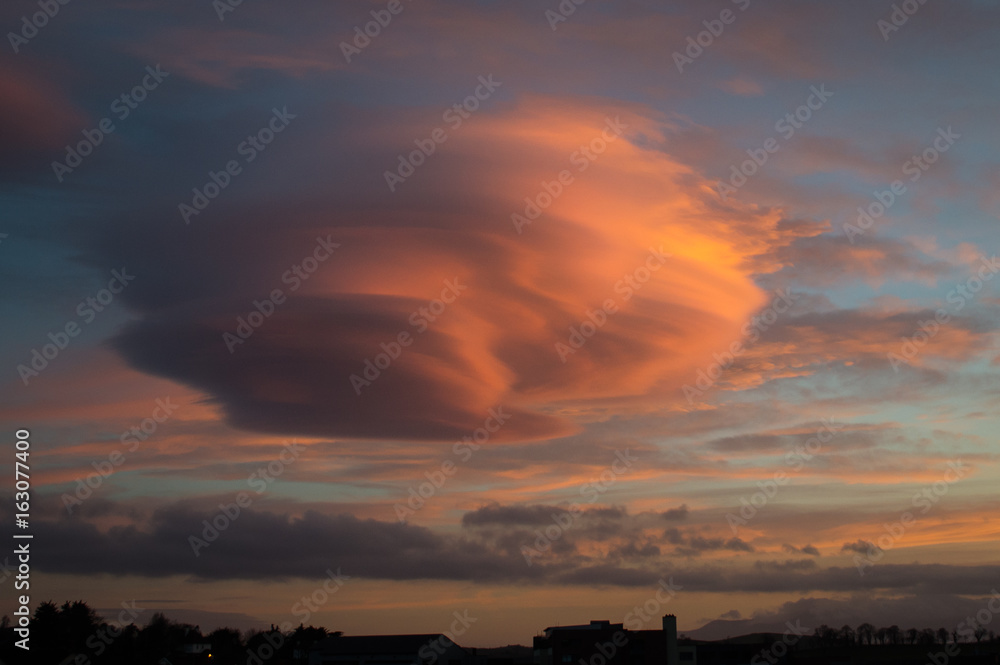 Naklejka premium Soczewkowata chmura o zachodzie słońca