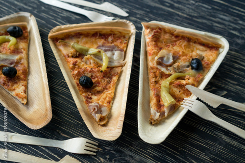 A slices of pizza is on a wooden plate.
