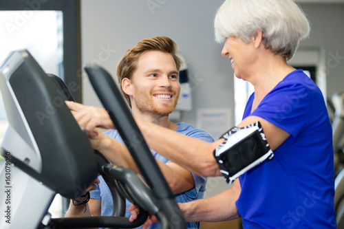 instructor aiding senior woman in gym