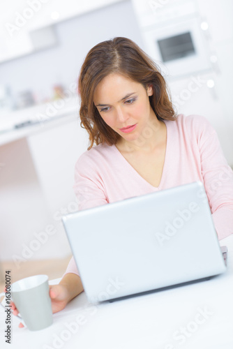 happy woman using laptop computer and drinking tea