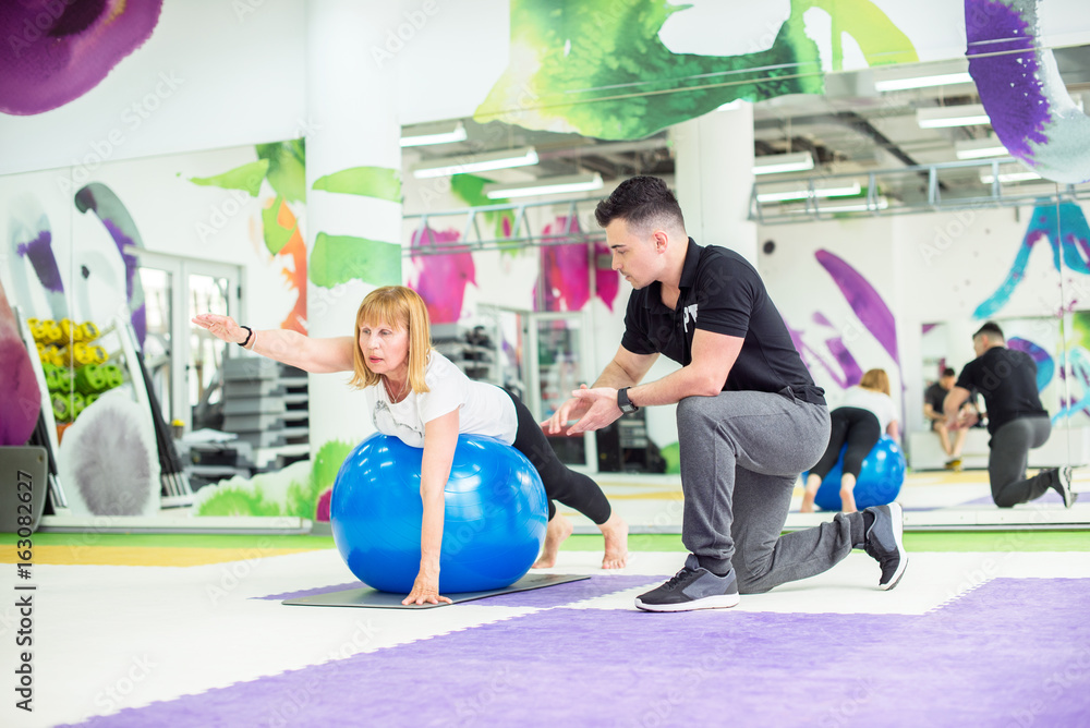 Obraz premium Senior woman is stretching with ball