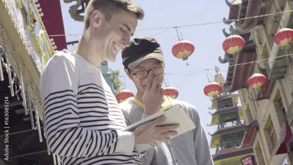 Man Uses His Tablet, His Boyfriend Asks Him To Take A Picture Of Him With Chinatown, San Francisco In The Background Man Uses His Tablet, His Boyfriend Asks Him To Take A Picture Of Him With Chinatown, San Francisco In The Background