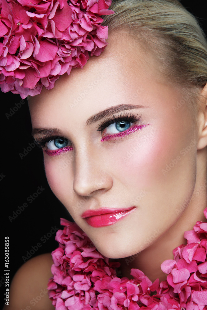 Close-up portrait of young beautiful woman with stylish sparlky make-up and pink flowers Close-up portrait of young beautiful woman with stylish sparlky make-up and pink flowers