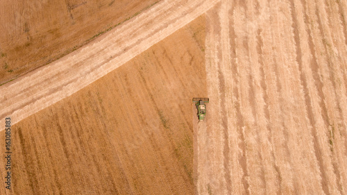Aerial shot of an agricultural wheat field and a combine harvester  in Europe