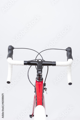 Bicycle Concept. Partial View of Professional Carbon Road Bike Handlebars, Frame and Duals With White Grip Tape. Against White