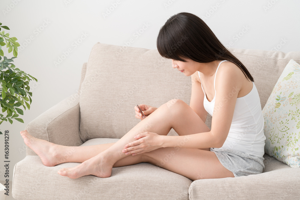 Obraz premium ピンセットで脱毛する女性、足