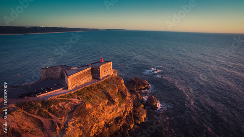 Aerial view of ocean and Nazare lighthouse at sunset, Portugal