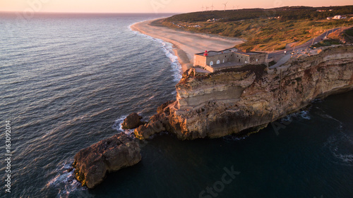 Aerial view of ocean, north Beach and Nazare lighthouse at sunset, Portugal