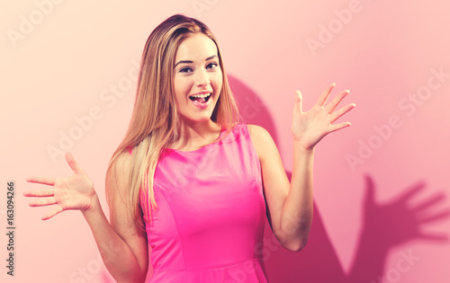 Surprised young woman posing on a pink background